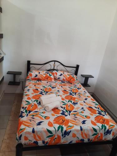 uma cama com um edredão florido com uma toalha em Departamento con pileta anisacate los talas em Anisacate