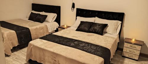 a bedroom with two beds and a night stand at Hotel Palo Grande in Manizales