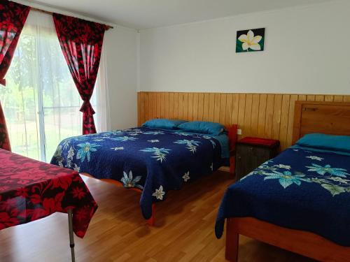a bedroom with two beds and a window at Hostal Kaiheke in Hanga Roa