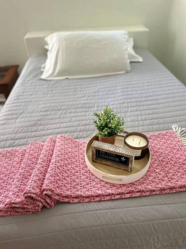 a bed with a pink blanket and a tray with a clock at Casa Estrellas in Santa Maria Huatulco