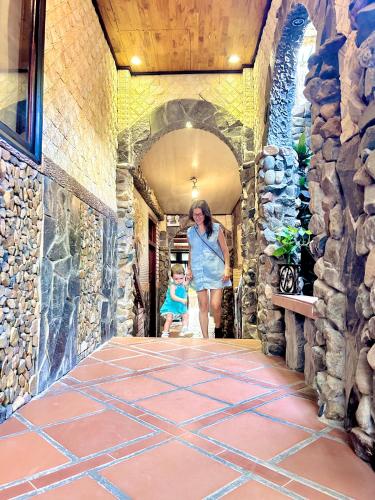 a woman and a child walking through a stone hallway at Sầm Sơn Boutique Hotel Phan Thiết in Phan Thiet