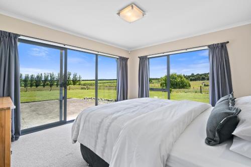 ein Schlafzimmer mit einem großen Bett und großen Fenstern in der Unterkunft Meadowscape Hideaway - Martinborough Holiday Home in Martinborough 