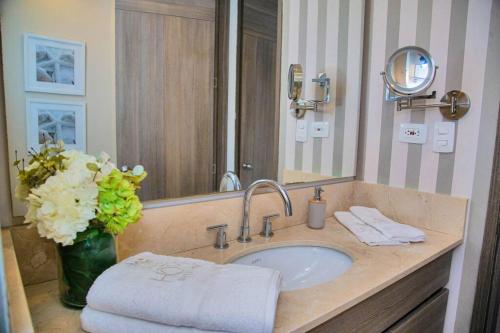 baño con lavabo y jarrón de flores en Luxury Beachfront Apartment - Morros City, en Cartagena de Indias