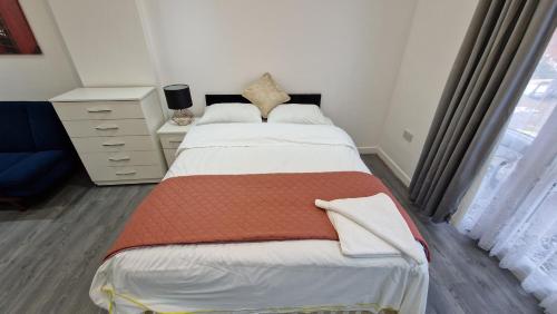 een slaapkamer met een bed, een dressoir en een raam bij Spacious 3-Bedroom Apartment - London in Wanstead