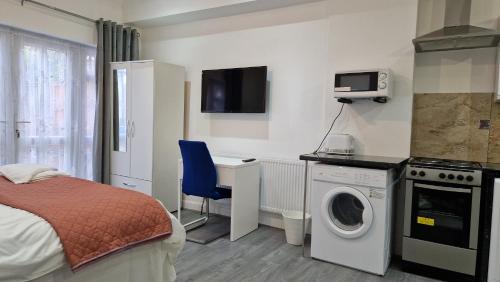 ein kleines Schlafzimmer mit einem Bett und einer Waschmaschine in der Unterkunft Spacious 3-Bedroom Apartment - London in Wanstead