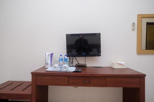 a wooden table with a television on top of it at UrbanView Hotel Anggraeni Jatibarang in Jatibarang
