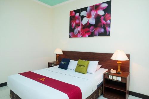 a bedroom with a bed and a painting on the wall at UrbanView Hotel Anggraeni Jatibarang in Jatibarang