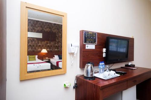 una camera d'albergo con specchio e TV di UrbanView Hotel Anggraeni Jatibarang 