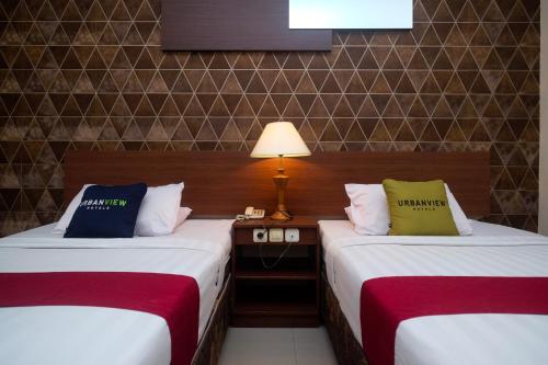 a hotel room with two beds and a lamp at UrbanView Hotel Anggraeni Jatibarang in Jatibarang