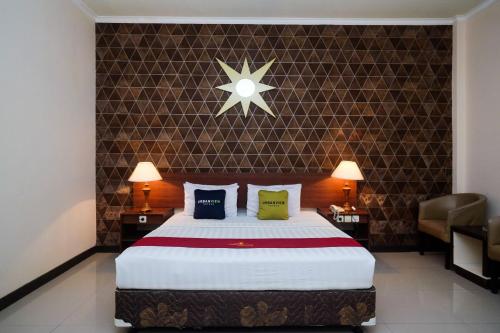 a bedroom with a large bed with two lamps and two chairs at UrbanView Hotel Anggraeni Jatibarang in Jatibarang