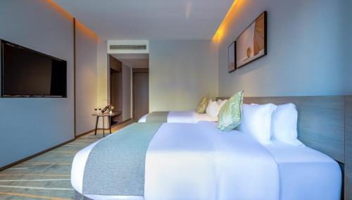 a hotel room with a large bed and a tv at Luzhou Baian Smart Hotel in Luzhou