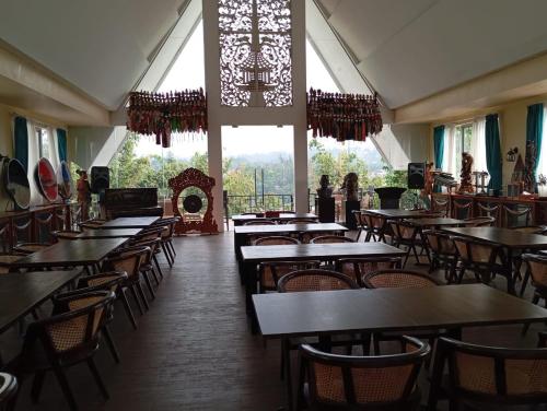 a restaurant with tables and chairs and a large window at The Culture Hotel And Gallery in Bogor
