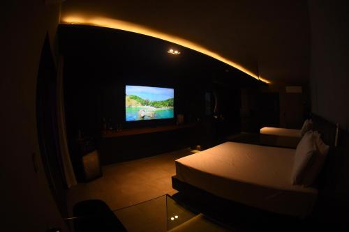 Habitación oscura con cama y TV. en All in Motel, en Garanhuns