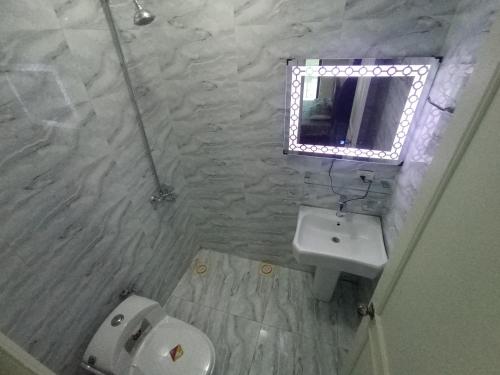 a bathroom with a sink and a toilet and a mirror at Bhurban 2bed townhouse with a lawn in Bhurban