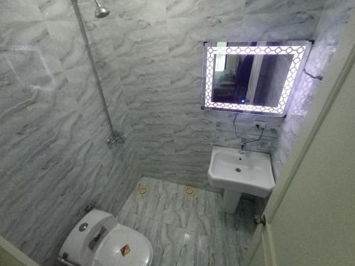 une salle de bain avec un lavabo, des toilettes et un miroir dans l'établissement Bhurban 2bed townhouse with a lawn, à Bhurban