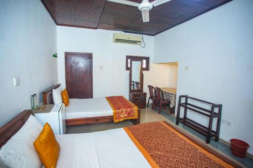 a bedroom with two beds and a table and chairs at Villa 6070 in Galle