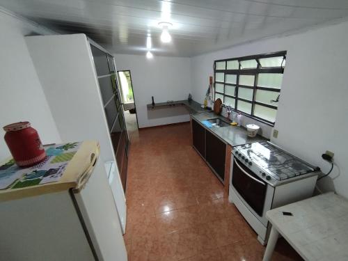 a small kitchen with a stove and a refrigerator at Canastra Hostel e Camping - quartos in Vargem Bonita