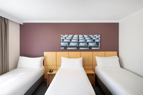 a room with two beds and a painting on the wall at Mercure Sydney Blacktown in Blacktown
