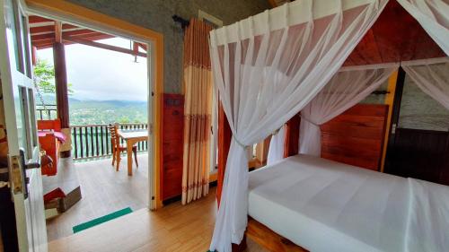 a bedroom with a canopy bed and a balcony at Guest Inn Avendra in Ella