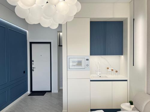 uma cozinha com armários brancos e uma porta azul em Квартира SMART №5 em Pavlodar