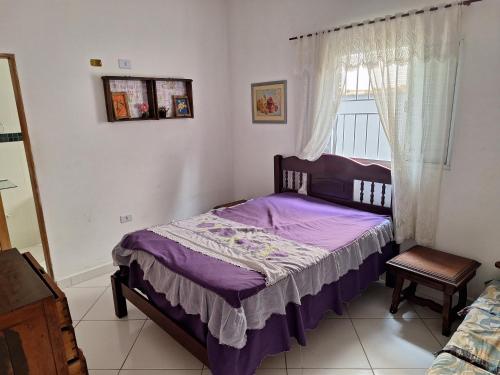 ein Schlafzimmer mit einem lila Bett und einem Fenster in der Unterkunft Casa para temporada em caraguatatuba praia do Massaguaçu in Caraguatatuba