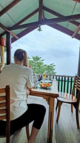 a woman sitting at a table with a plate of food at Guest Inn Avendra in Ella