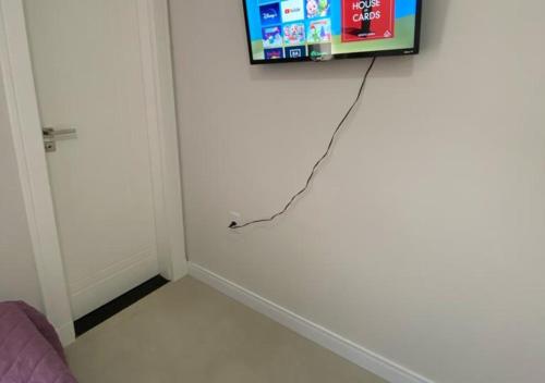 einen Fernseher mit einer Leine an einer weißen Wand in der Unterkunft Suíte Premium in Itajaí