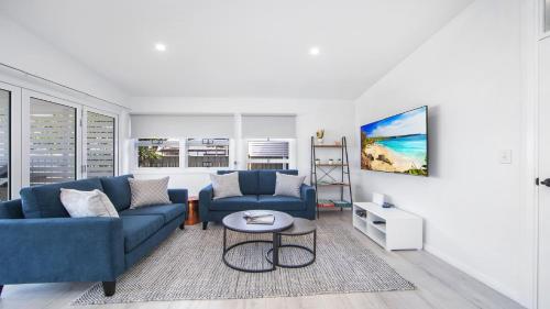 a living room with two blue couches and a table at Ettalong Beach House in Ettalong Beach