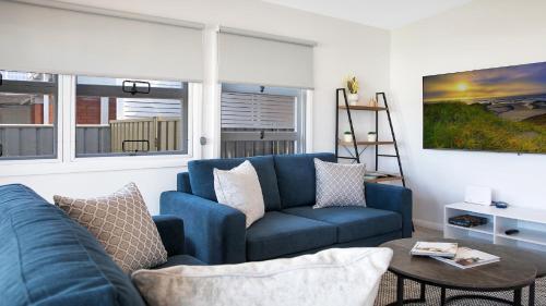 a living room with a blue couch and a table at Ettalong Beach House in Ettalong Beach