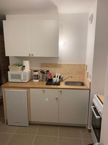 a small kitchen with white cabinets and a sink at T2 pied de piste + Parking in Les Déserts