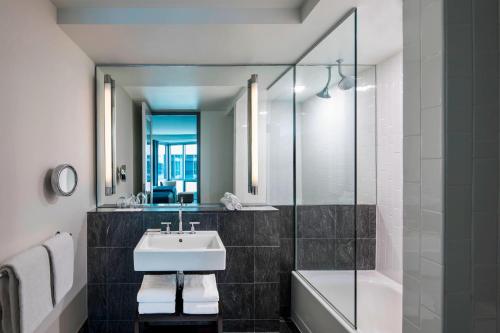 La salle de bains est pourvue d'un lavabo, d'une baignoire et d'un miroir. dans l'établissement W Hoboken, à Hoboken