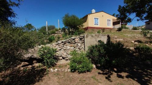 ein Haus auf einem Hügel mit einer Steinmauer in der Unterkunft El Roble, casa de sierra in Estancia Vieja