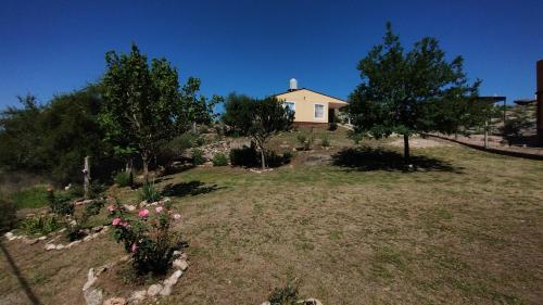ein Haus auf einem Hügel mit Blumen im Hof in der Unterkunft El Roble, casa de sierra in Estancia Vieja