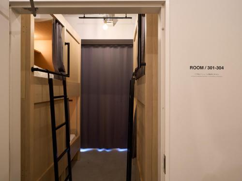 a room with a door and a curtain and a television at Hotel Plus Hostel TOKYO ASAKUSA 1 in Tokyo