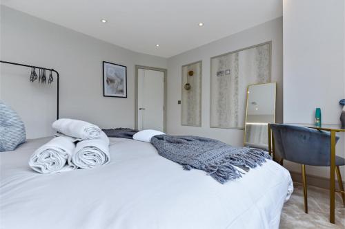 a bedroom with a white bed with towels on it at Contemporary 2 Bedroom Flat in Excellent Location! in London
