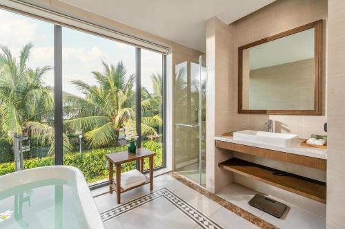 un bagno con vasca, lavandino e finestra di Andochine Villas Resort & Spa Phu Quoc - All Villas with Private Pool a Phu Quoc