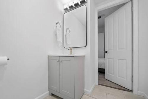 La salle de bains blanche est pourvue d'un miroir et d'un lavabo. dans l'établissement Charming Mt. Adams 1BR - Near Downtown & Stadiums, à Cincinnati
