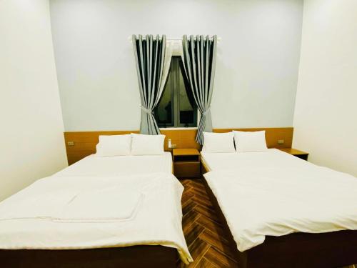 two beds in a room with a window at Khách sạn Mimosa in Kon Plong