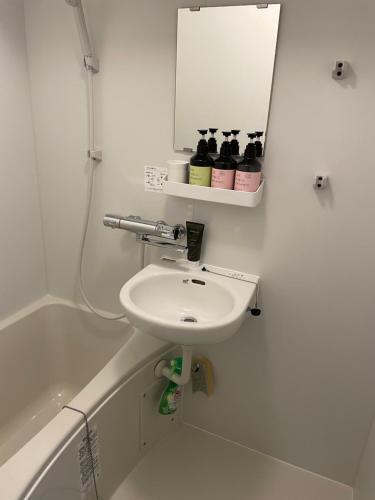 La salle de bains blanche est pourvue d'un lavabo et d'un miroir. dans l'établissement Kamatas STAY 京急蒲田駅 徒歩5分, à Tokyo