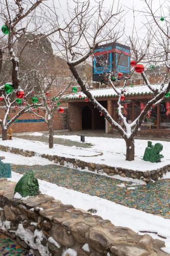 a garden with christmas decorations on trees in the snow at Brickyard Retreat at Mutianyu Great Wall Adjoin to Mutianyu Great Wall - Room with the View of Great Wall - Chinese massage experience - Vehicle Shuttle Service - International Catering - SPA& Nail Beauty Facilities in Huairou