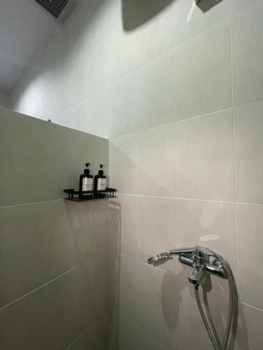 ein Badezimmer mit Dusche und zwei Flaschen auf einem Regal in der Unterkunft Chua Guest house Canggu in Canggu