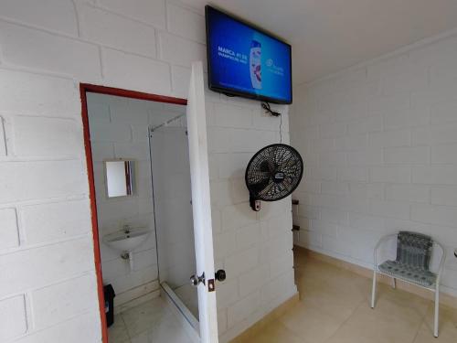 ein Bad mit einem TV und einem Ventilator an der Wand in der Unterkunft Hospedaje Los Jazmines de Santa Rosa in Tarapoto