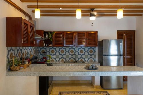 a kitchen with a stainless steel refrigerator and wooden cabinets at Casa Pakal Valladolid in Valladolid