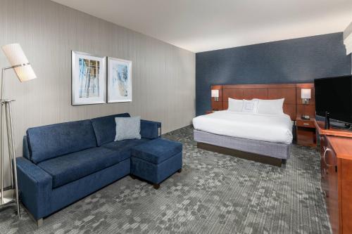 une chambre d'hôtel avec un lit et un canapé bleu dans l'établissement Courtyard by Marriott San Diego Oceanside, à Oceanside