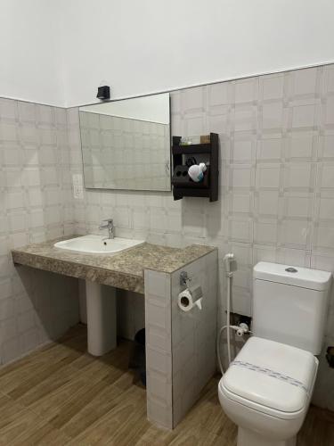 a bathroom with a sink and a toilet and a mirror at Sigiriya Cottage in Sigiriya