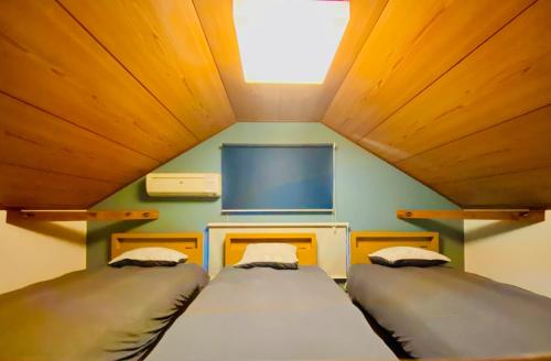 two beds in a small room with a tv at Pyrenees Cottage - Vacation STAY 24861v in Hakuba