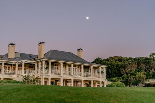 a large house on top of a green hill at Rosewood Kauri Cliffs in Matauri Bay