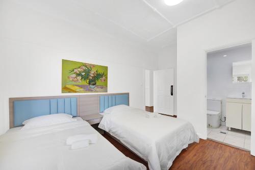 two beds in a bedroom with white walls and wood floors at Dream Vintage Place in Chatswood in Sydney