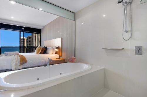uma casa de banho branca com uma banheira e uma cama em Circle on Cavill - Ocean Facing - Self Contained, Privately Managed em Gold Coast