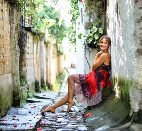 a woman in a dress sitting on the side of a building at Unicorn Reborn - Peaceful Rentals in San Marcos La Laguna